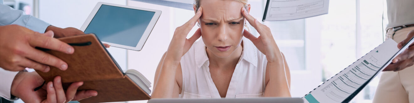 Femme stressée au travail entourée de documents.