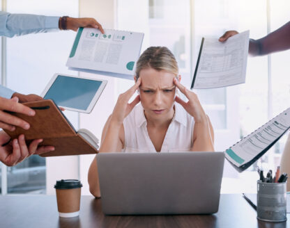 Femme stressée au travail entourée de documents.