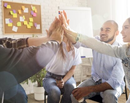 Équipe réunie pour un high-five énergétique au bureau.